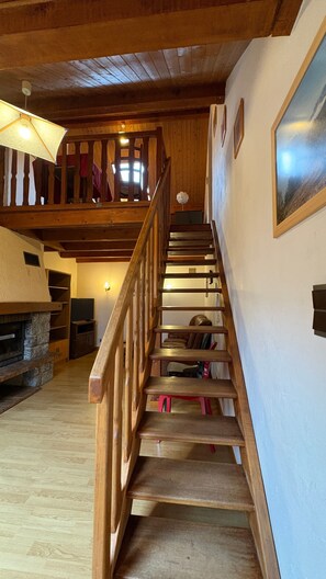 A wooden staircase leading to a loft area with a fireplace, a television, and a framed picture on the wall. - Apartment 'Logement Entier 8 Couchages Wifi' with Mountain View and Wi-Fi (Saint François Longchamp)