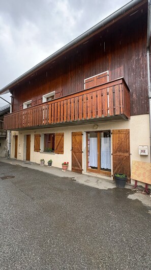 A two-story building with a wooden balcony, potted plants, and a visible mailbox. - Apartment 'Logement Entier 8 Couchages Wifi' with Mountain View and Wi-Fi (Saint François Longchamp)