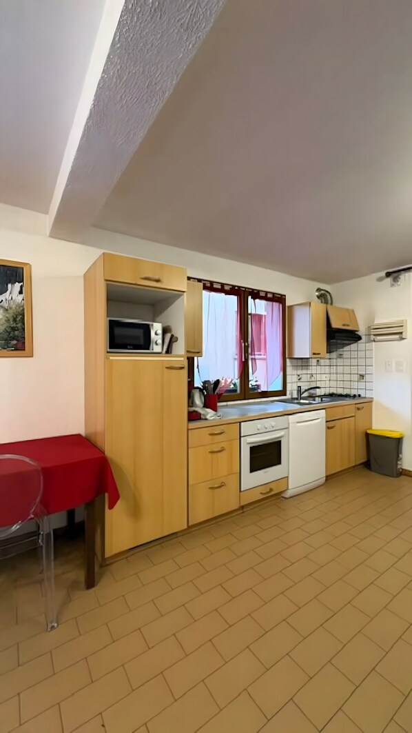 A compact kitchen with wooden cabinets, a microwave, a stove, and a sink.