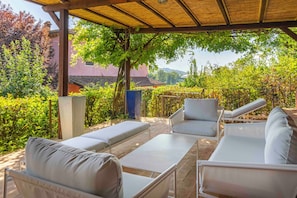 An outdoor seating area with a pergola, cushioned chairs, and a table. - Podere Gora (Toscana)