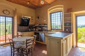 A kitchen with a dining area, equipped with a stove, oven, and dishwasher. - Podere Gora (Toscana)