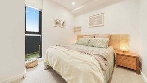 Ein Schlafzimmer mit einem Bett, einem Nachttisch, einer Lampe und einem Bild an der Wand.