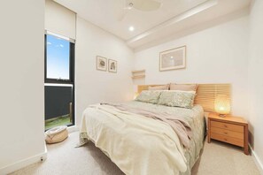 Ein Schlafzimmer mit einem Bett, einem Nachttisch, einer Lampe und einem Bild an der Wand.