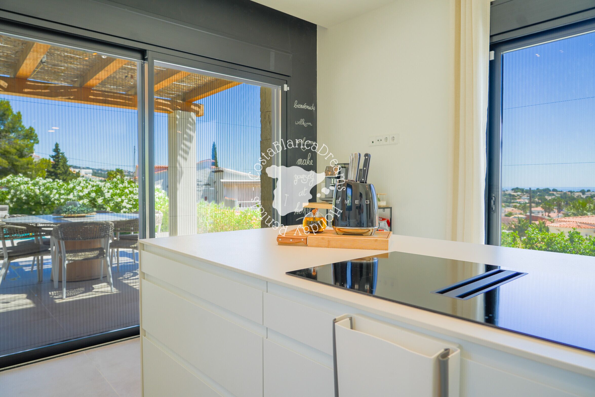 Een moderne keuken met een groot raam, een koffieapparaat en uitzicht op groen.