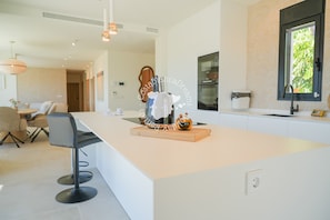A modern kitchen with a central island, bar stools, and pendant lighting. - CostaBlancaDreams - Villa Ortenbach in Calpe (Calpe / Calp)