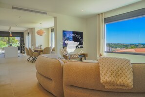 A modern living room with a large window, a sofa, a dining area, and a kitchen. - CostaBlancaDreams - Villa Ortenbach in Calpe (Calpe / Calp)