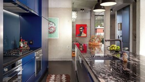 Uma cozinha moderna com armários azuis, bancada de mármore e vista para a cidade.