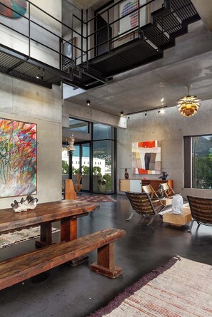 Um loft espaçoso com pé direito alto, paredes de concreto aparente e grandes janelas com vista para a cidade.