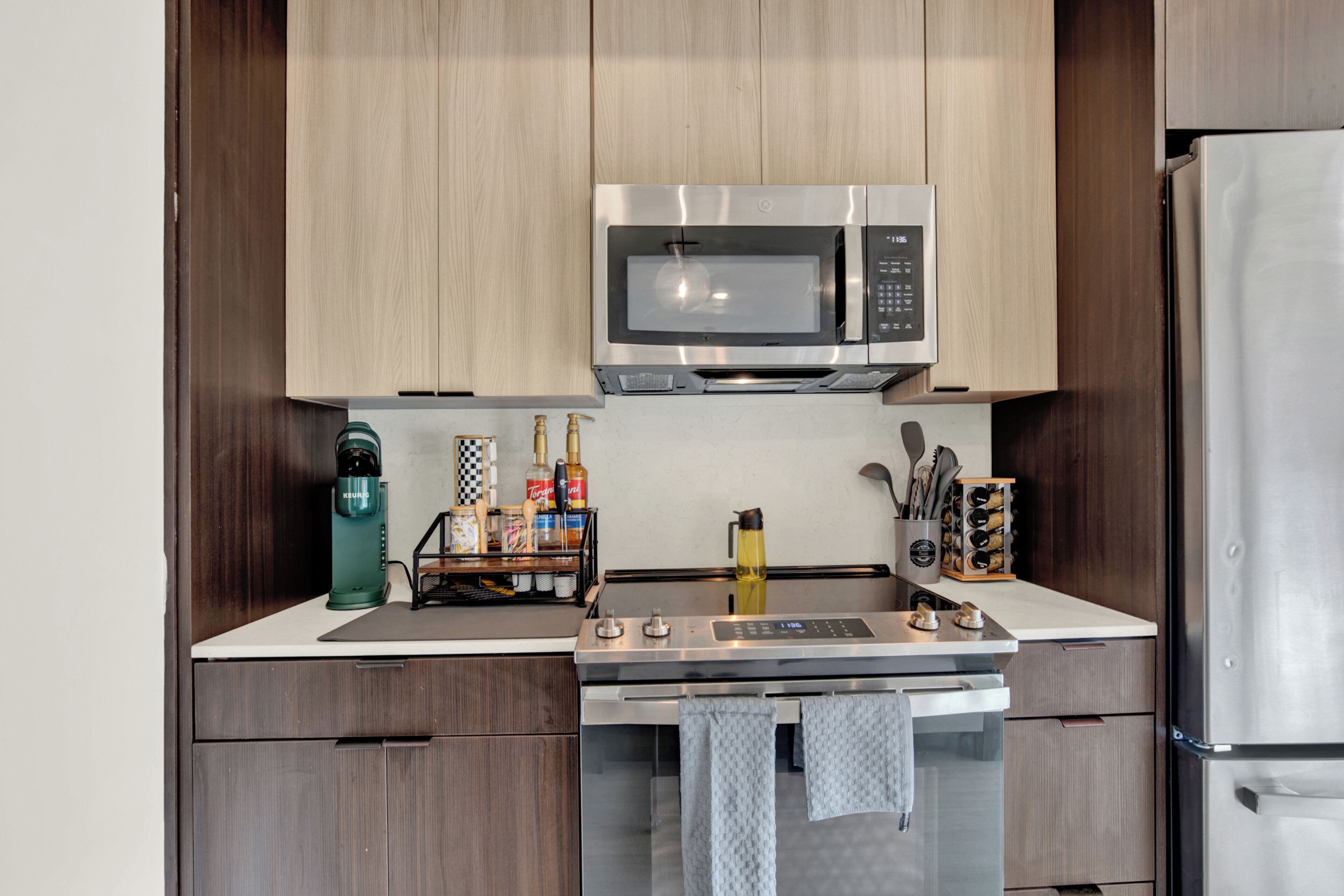 A compact kitchen with a built-in microwave, a coffee maker, and a wine cooler.