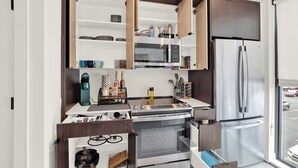 Une cuisine compacte dotée d’appareils électroménagers intégrés, notamment un four à micro-ondes, un four et un réfrigérateur.