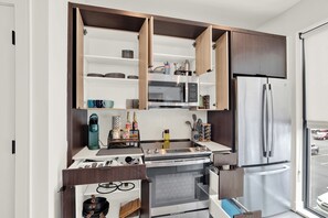 Eine kompakte Küche mit integrierten Geräten, darunter Mikrowelle, Backofen und Kühlschrank.