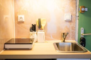 Un plan de travail de cuisine avec un ordinateur portable, un porte-couteaux et un évier.