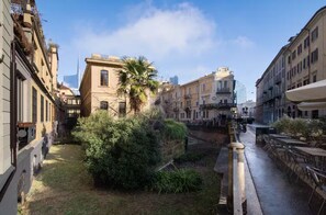 A narrow urban street with historic buildings, a palm tree, and a canal. - Brera Penthouse - View of Porta Nuova (Milano)