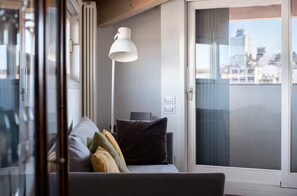 Ein modernes Wohnzimmer mit einer Couch, einer Stehlampe und einer Schiebeglastür, die auf einen Balkon führt.