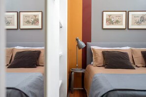 Et hotelværelse med to senge, et natbord, en lampe og billeder på væggene.