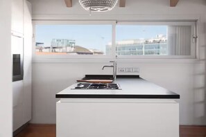 Et moderne køkken med gaskogeplade, vask og et vindue med udsigt til bygninger.