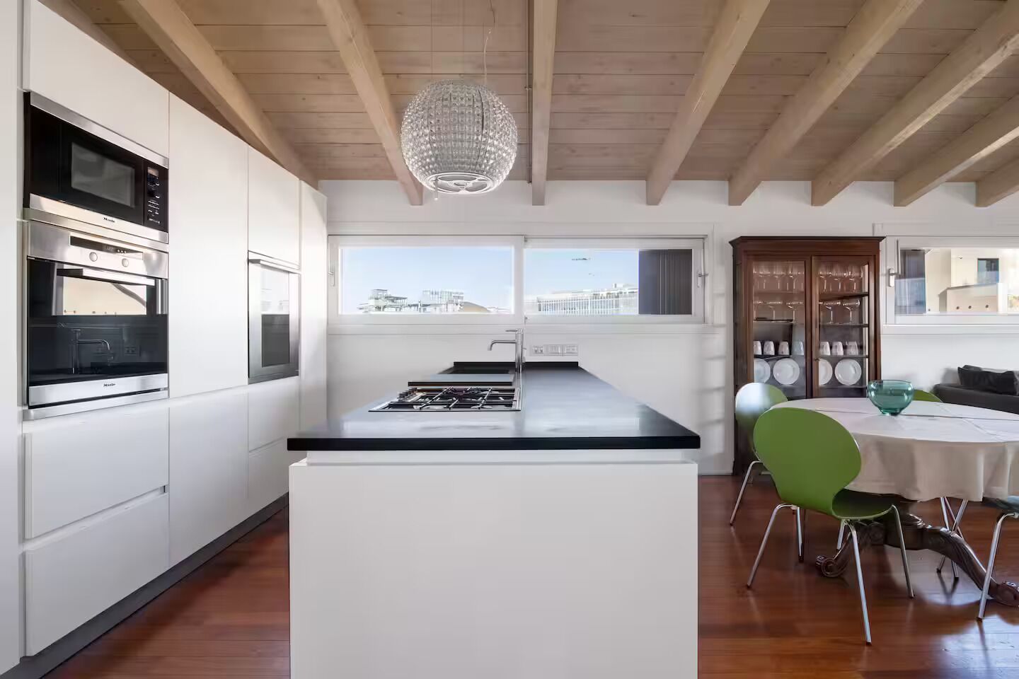 Eine moderne Küche mit Kochinsel, integrierten Geräten und einem Essbereich mit Tisch und Stühlen.