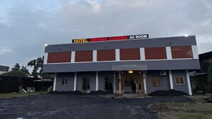 Un edificio de dos pisos con un cartel que dice 'HOTEL KRISHNA GARDEN AC ROOM'.