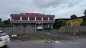 Un hotel llamado 'Hotel Krishna Garden' con un letrero de habitación con aire acondicionado, una cerca de hormigón y un coche estacionado al frente.