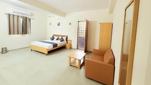 Una habitación con cama, sofá, mesa y espejo.