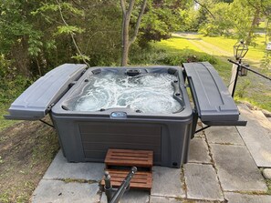 Ein Whirlpool mit Bedienfeld, zwei seitlichen Erweiterungen und einer hölzernen Fußstütze.
