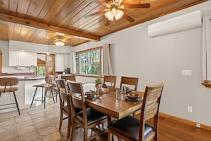 A wooden dining table with chairs, a ceiling fan, and a window with curtains. - Canandaigua Lake | Near Wineries | Sleeps up to 10 | Hot tub (Rushville)