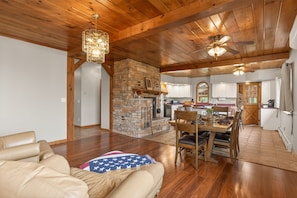 A spacious living room with a stone fireplace, wooden ceiling, and a dining area with a table and chairs. - Canandaigua Lake | Near Wineries | Sleeps up to 10 | Hot tub (Rushville)