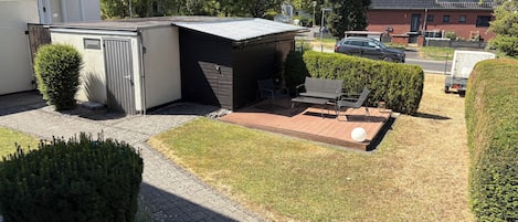 A residential area with a small patio, a shed, and a car parked nearby.