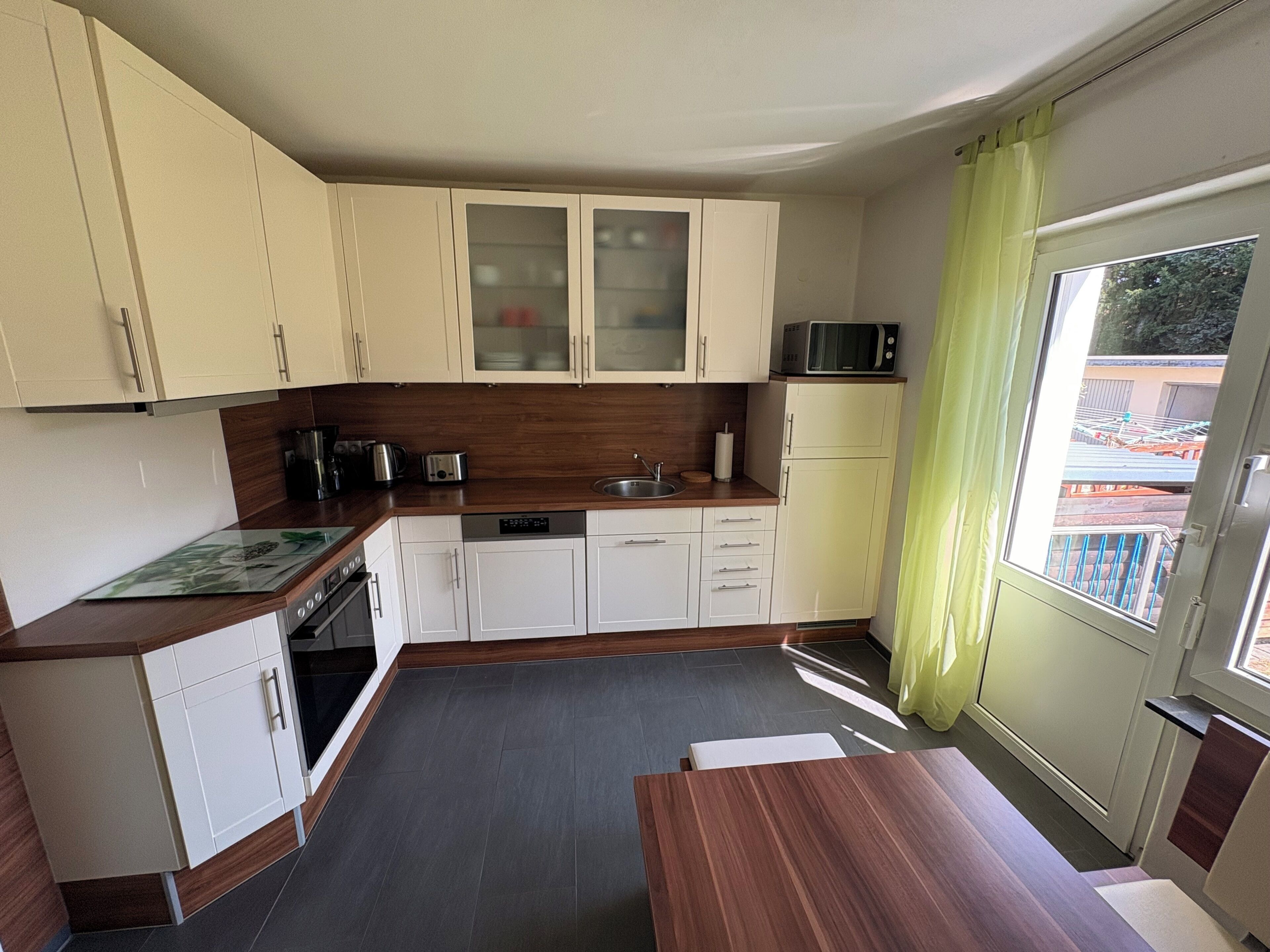 A compact kitchen with white cabinets, a microwave, and a window with a view of a building outside.