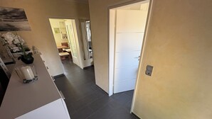 En gang med en hvid dør, et glasbord med et lys og en plante.