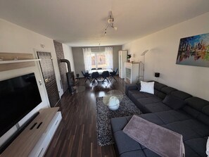 Ein modernes Wohnzimmer mit Flachbildfernseher, einer Couch, einem Teppich und einem Kamin.