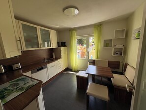 Una cocina compacta con comedor, microondas y ventana con cortinas.