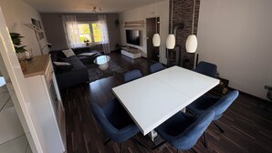 En moderne stue med en sofa, et spisebord og et fjernsyn.