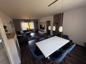 Ein modernes Wohnzimmer mit einer Couch, einem Esstisch und einem Fernseher.