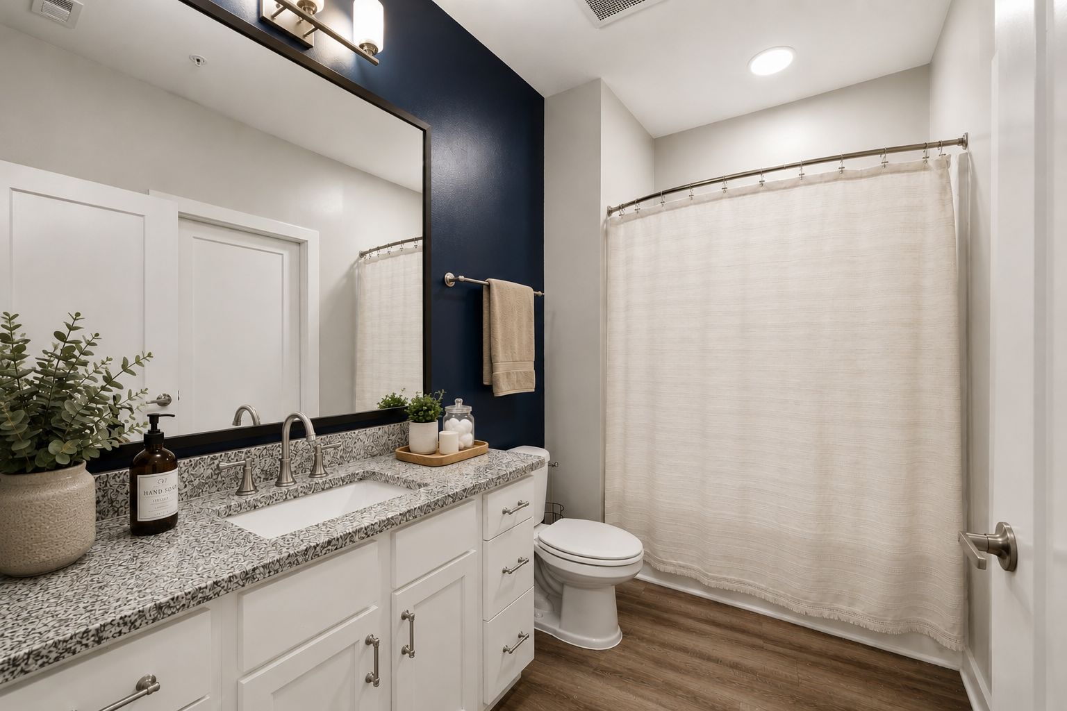 A bathroom with a white sink, a mirror, a toilet, and a shower curtain.