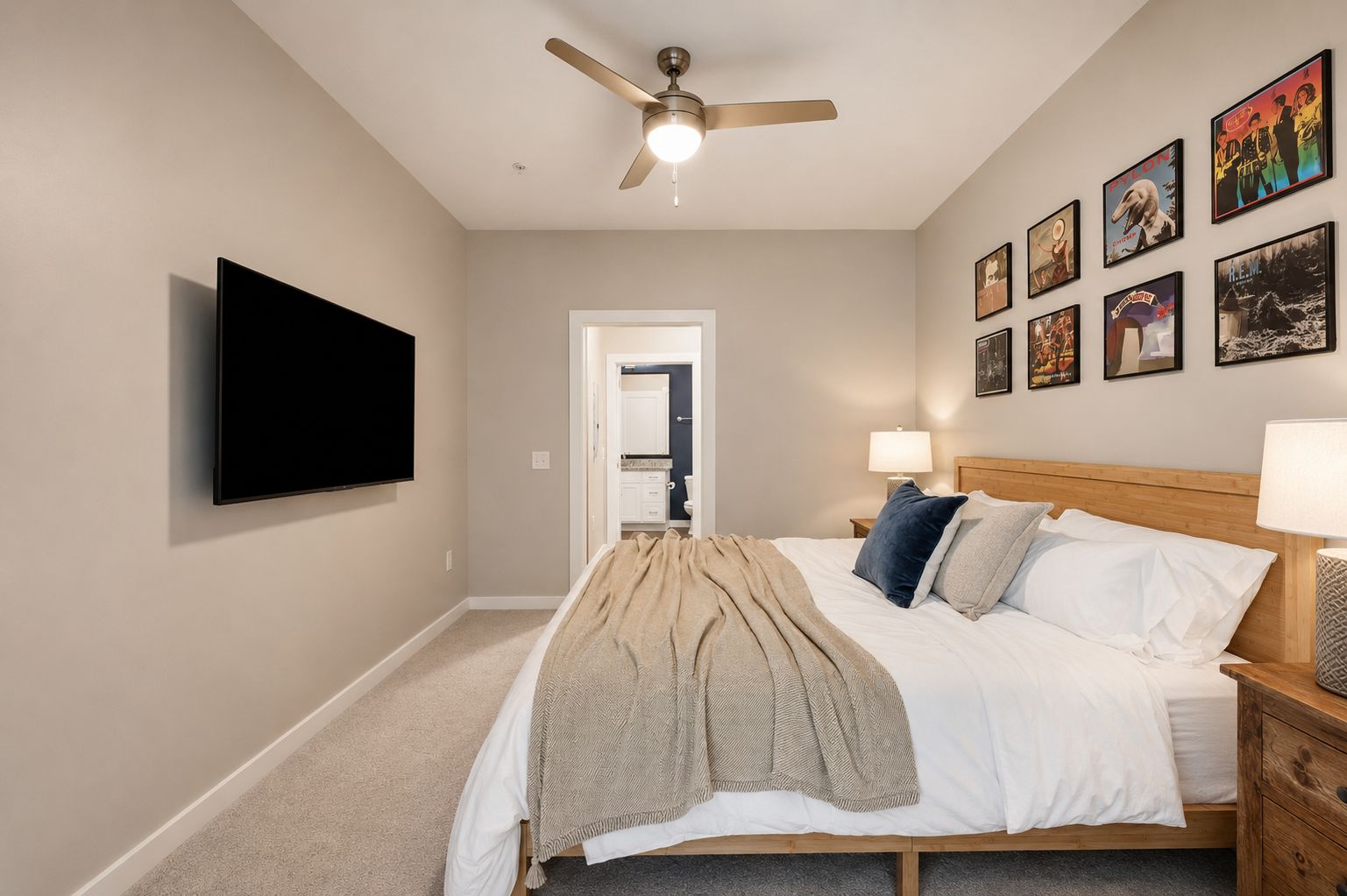 A bedroom with a bed, a ceiling fan, a TV, and wall art.