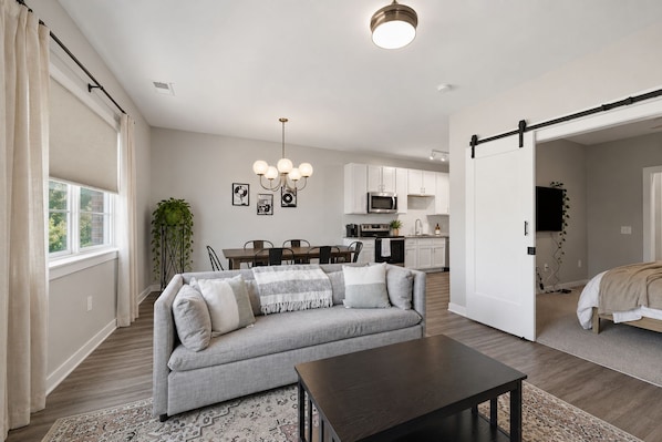 A modern living room with a sofa, a coffee table, and a dining area with chairs.