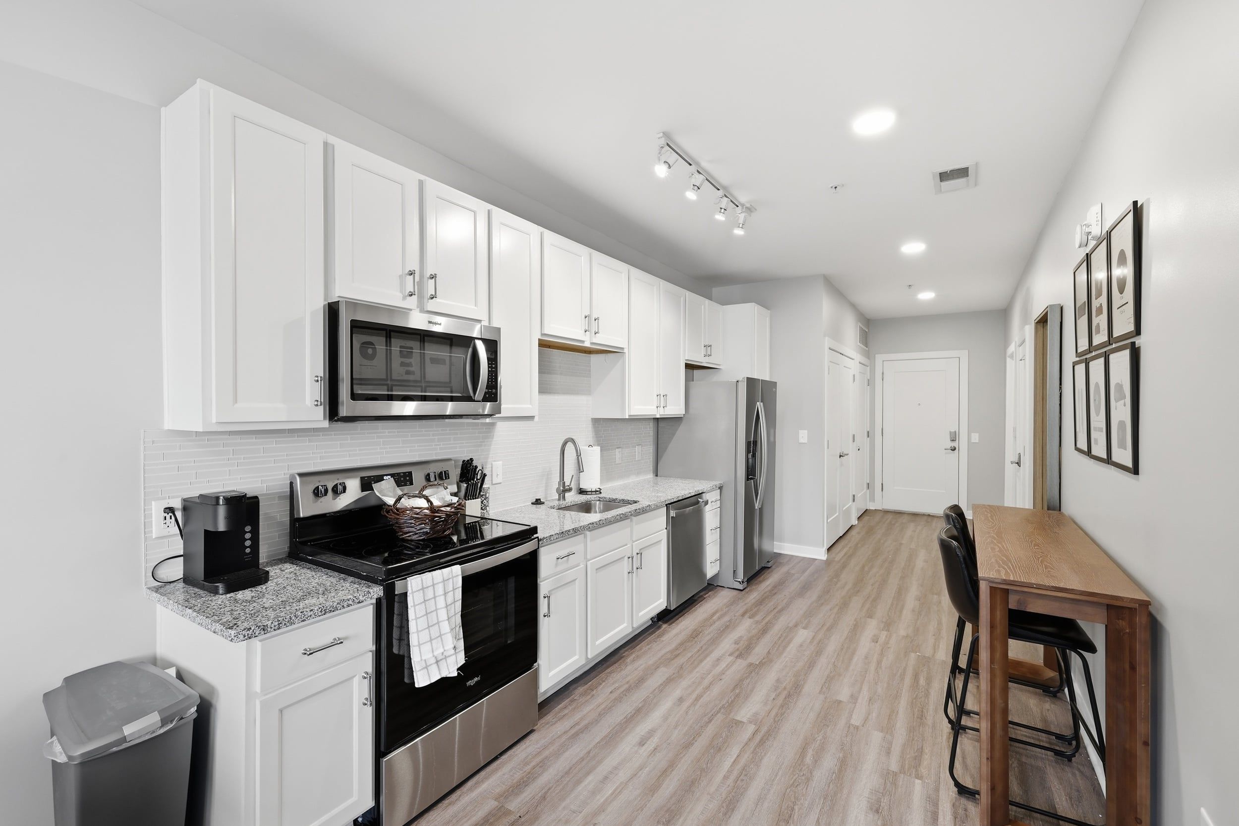 A modern kitchen with white cabinets, stainless steel appliances, and a wooden dining table.