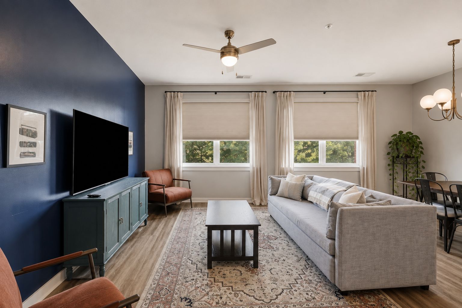 A modern living room with a flat-screen TV, a sofa, a coffee table, and a ceiling fan.