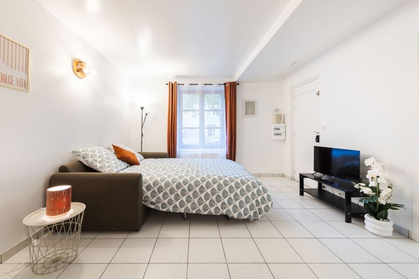 Un dormitorio moderno con cama, televisor y una planta en maceta.
