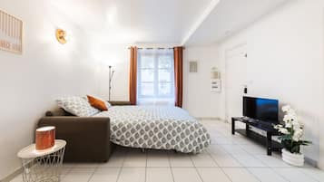 Un dormitorio moderno con cama, televisor y una planta en maceta.