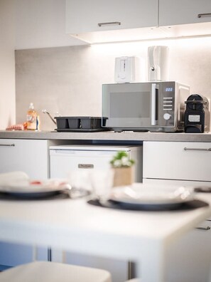Una cocina moderna con microondas, cafetera y un lavamanos pequeño.