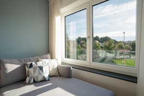 Una sala de estar moderna con un ventanal grande, un sofá con cojines estampados y vistas a una zona residencial.
