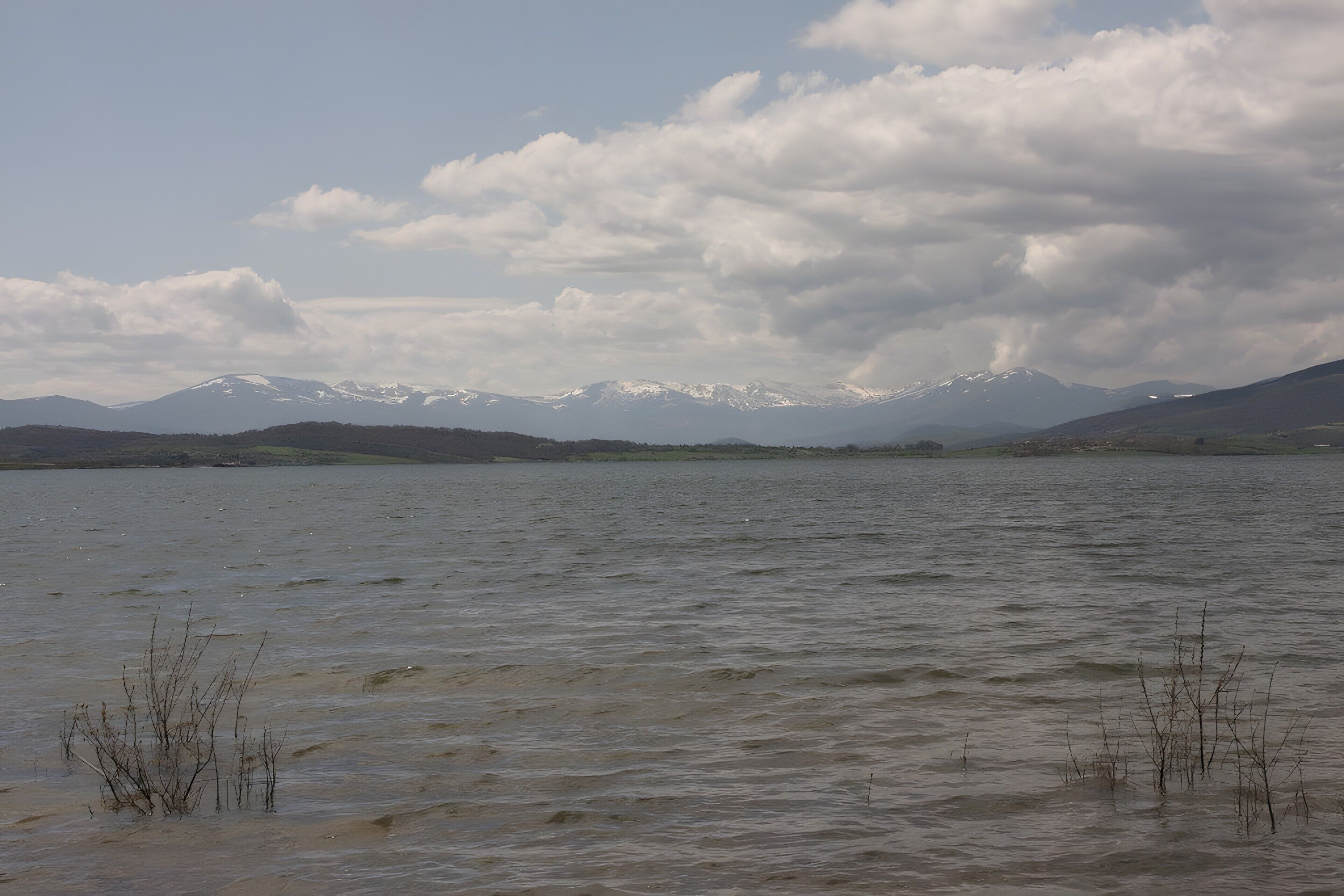 A lake with mountains in the background and some vegetation in the foreground.