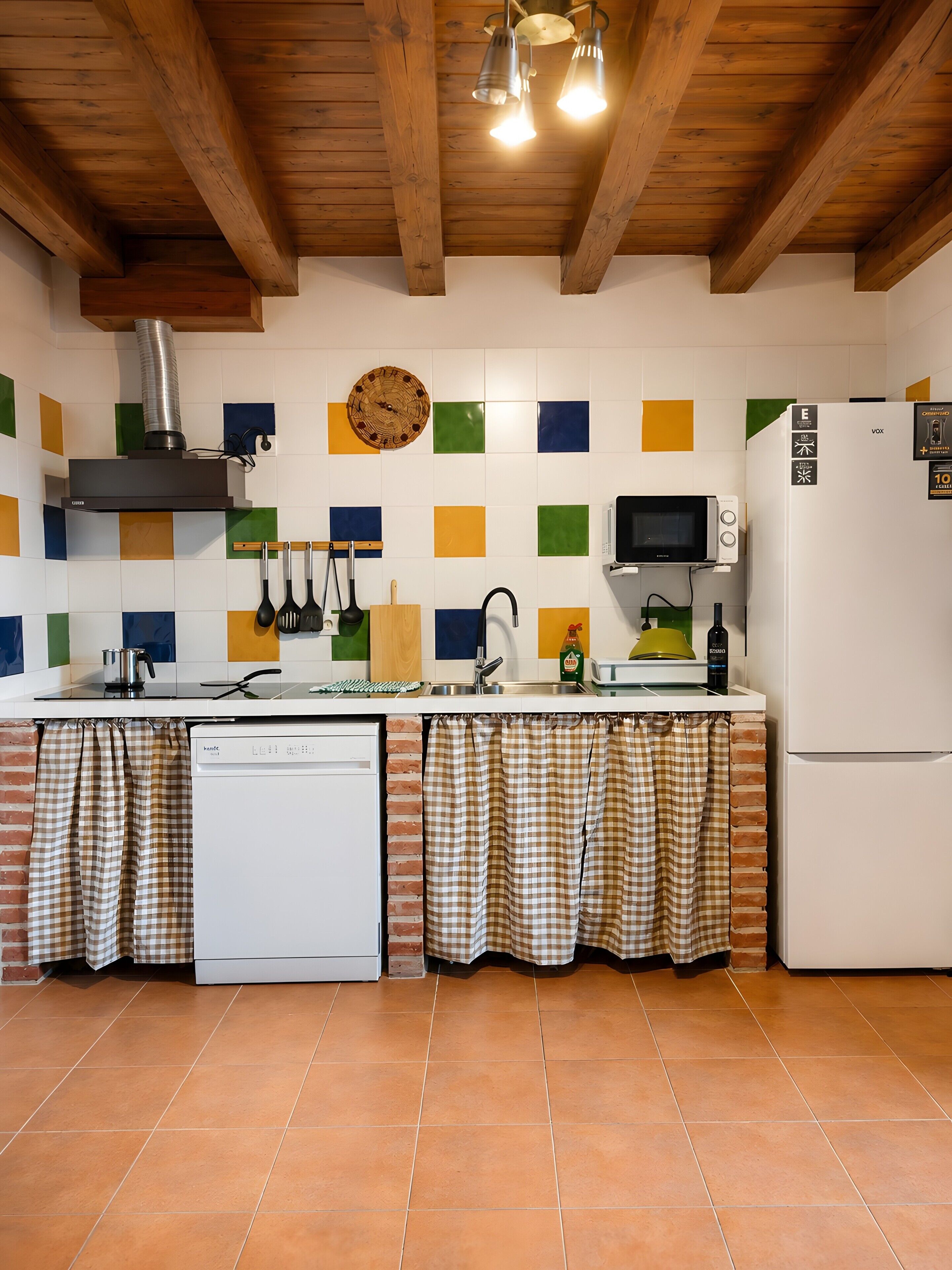 Una cocina con techo de madera, estufa, microondas, refrigerador y lavavajillas.