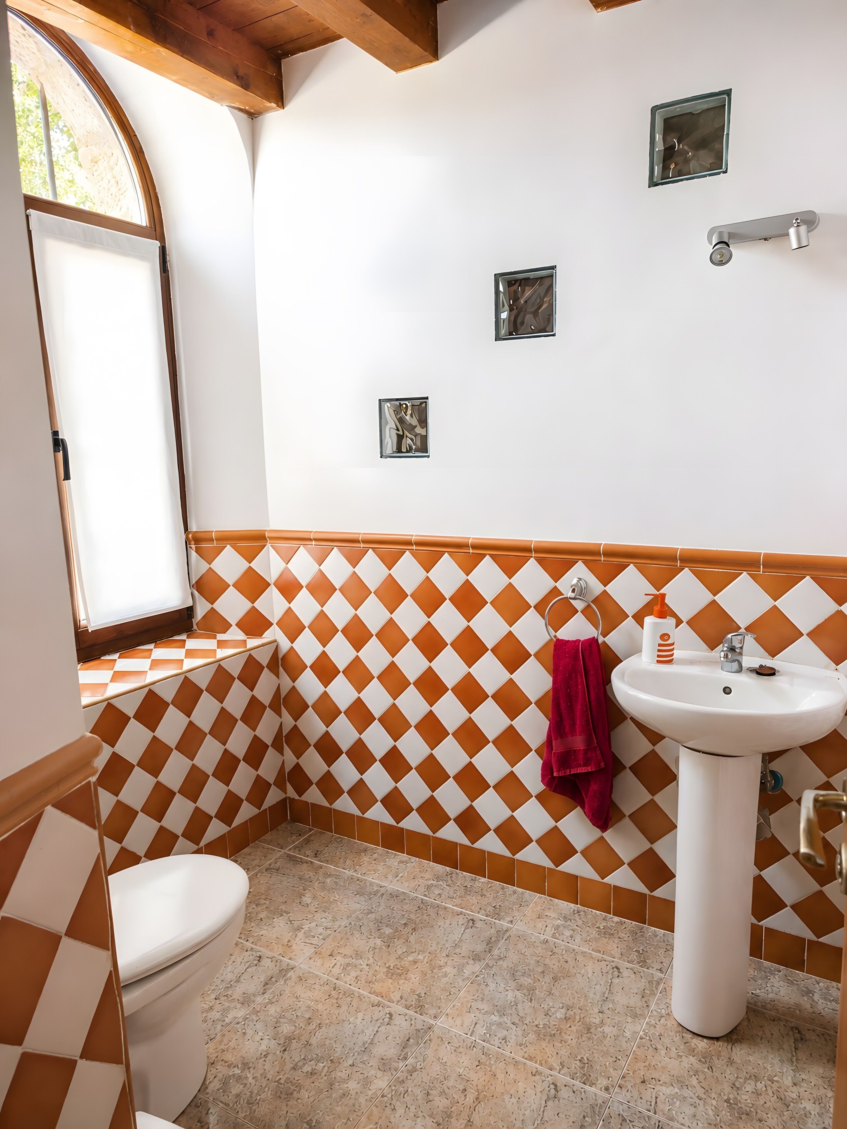 A bathroom with a white sink, a red towel, and a checkered wall pattern.