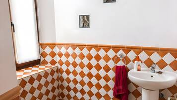 A bathroom with a white sink, a red towel, and a checkered wall pattern.