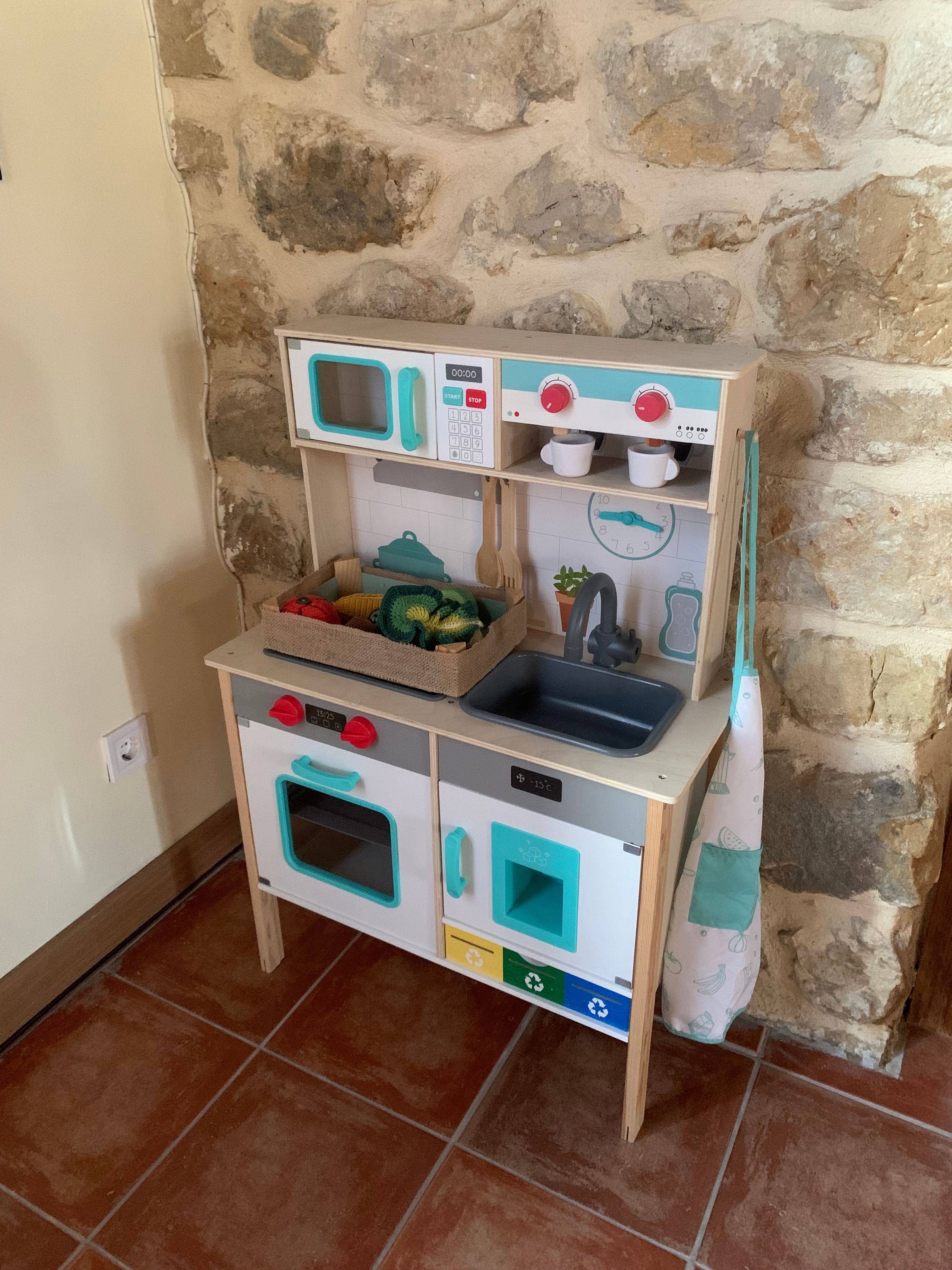 Una cocina de juguete para niños con un fondo de pared de piedra, un lavabo y un reloj.