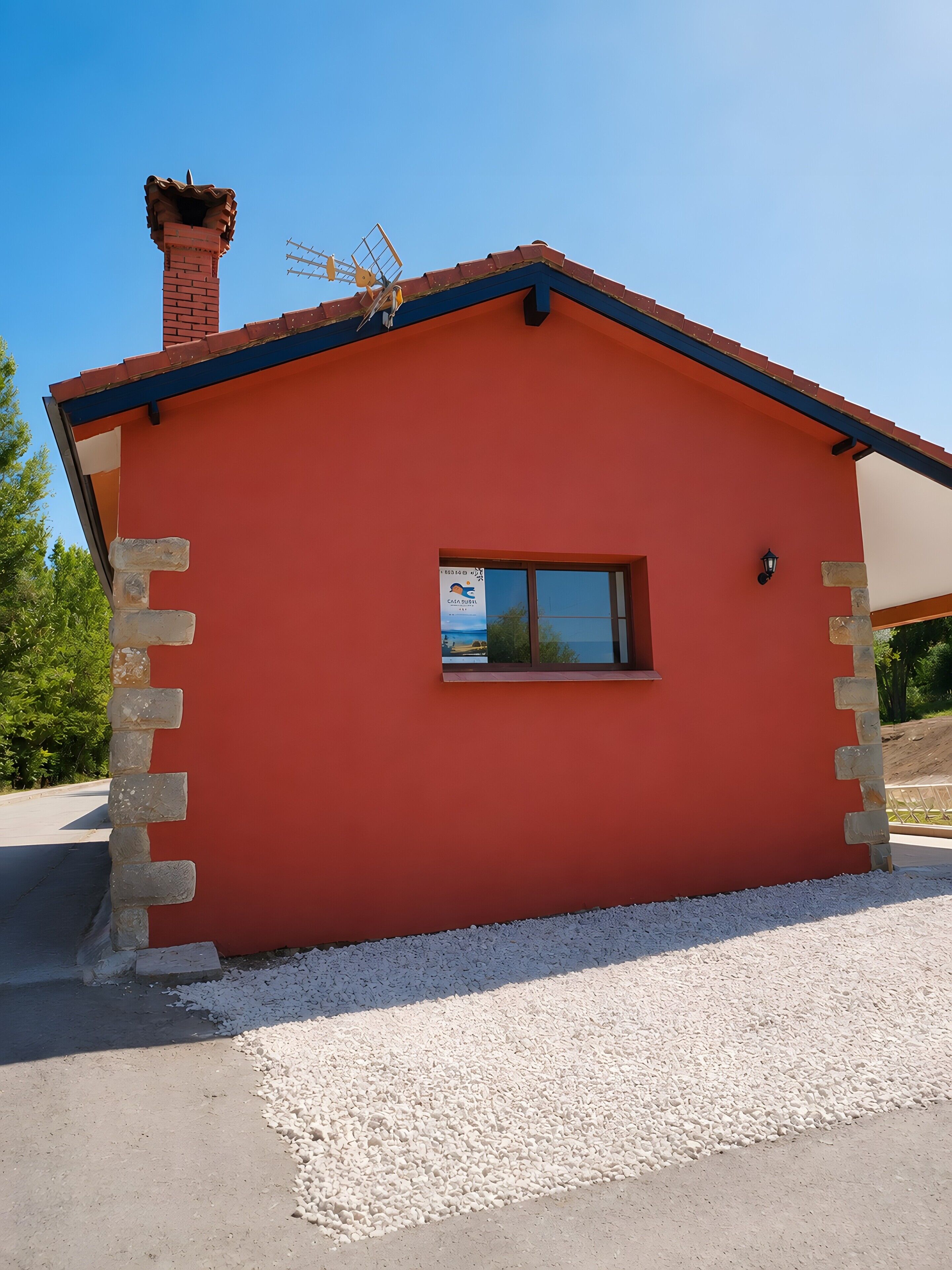 Un edificio pequeño de un piso con fachada roja, una chimenea y una ventana con un letrero.