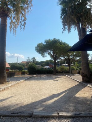 A clear sky with a sandy ground, trees, and a building in the background. - 2-Bedroom Apartment – On the Banks of the Siagne, with Pool & Parking (Mandelieu-la-Napoule)